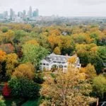 Aerial shot of Duke mansion surrounded by trees with a city skyline in the background