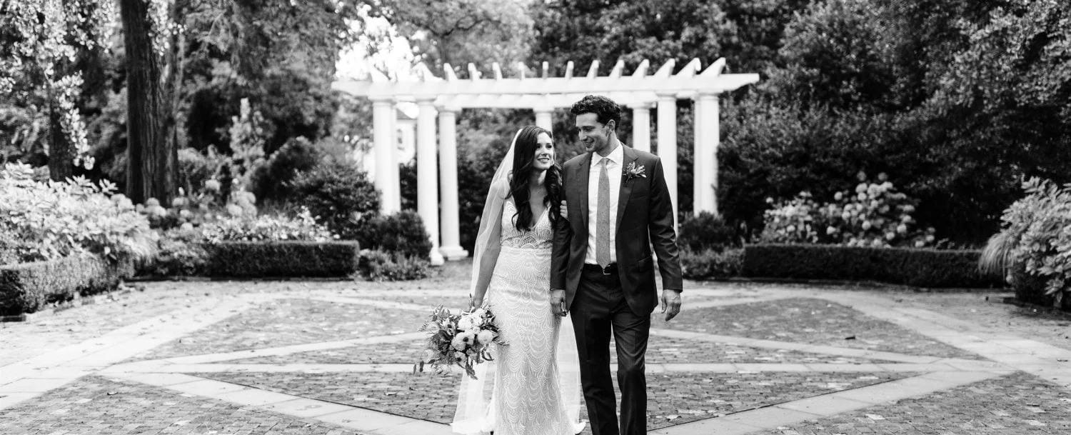 A bride and groom in front of a pergola.