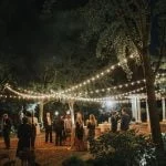 A rehearsal dinner in the courtyard beneath hanging lights.
