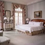 Ornate bedroom at Duke Mansion with fine curtains and doors to an outer porch.